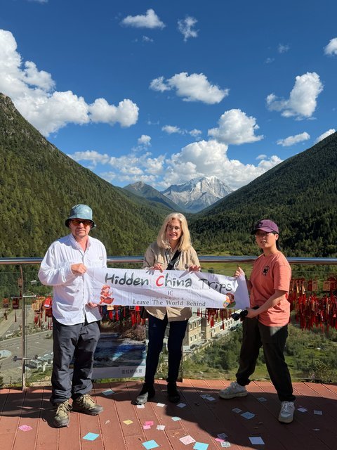 Travelers with Hidden China Trips banner, snow mountain viewpoint