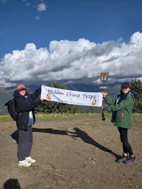 Travelers with Hidden China Trips banner at the G318 milestone sign