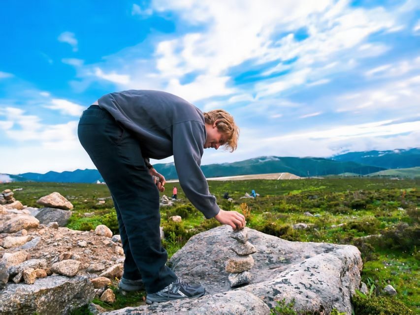 Traveler stacking stones on the grassland
