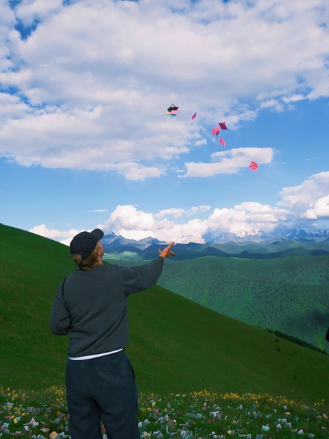 Traveler throwing prayer papers into the sky over green hills