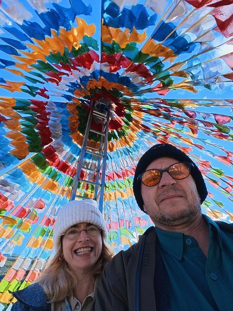 Travelers under a canopy of colorful prayer flags