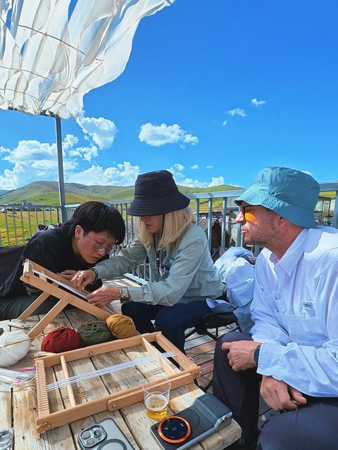 Travelers trying traditional weaving craft