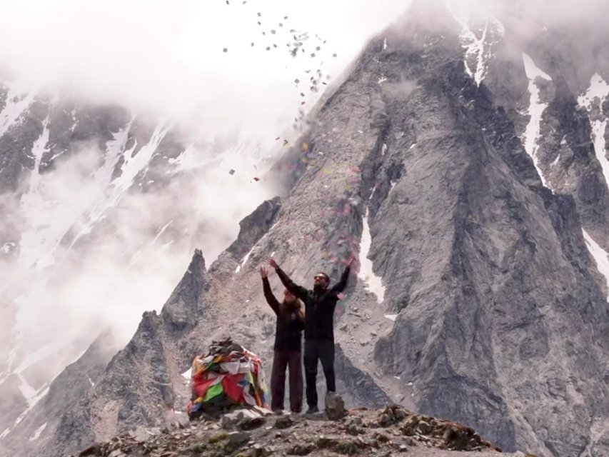 Couple throwing prayer papers into the air on a misty peak