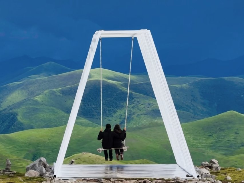 Couple on a swing overlooking green hills