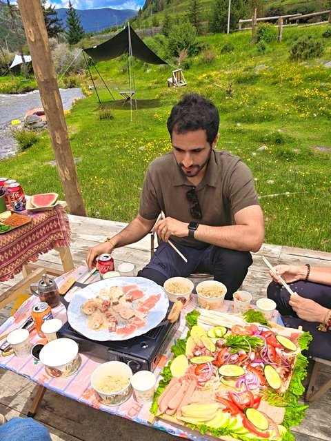 Travelers sharing a barbecue picnic by the river