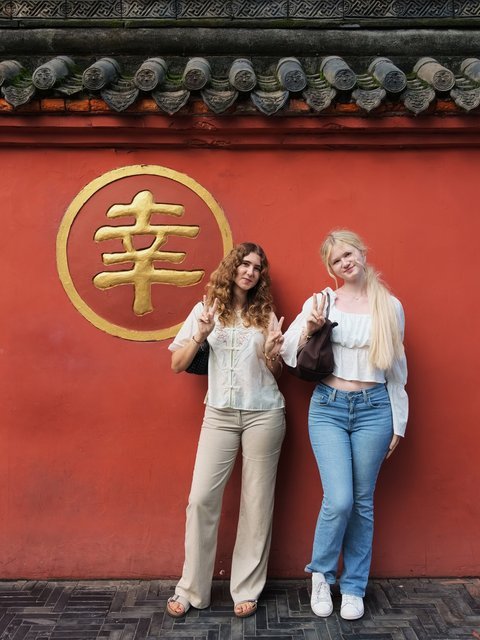 Travelers in front of a red temple wall